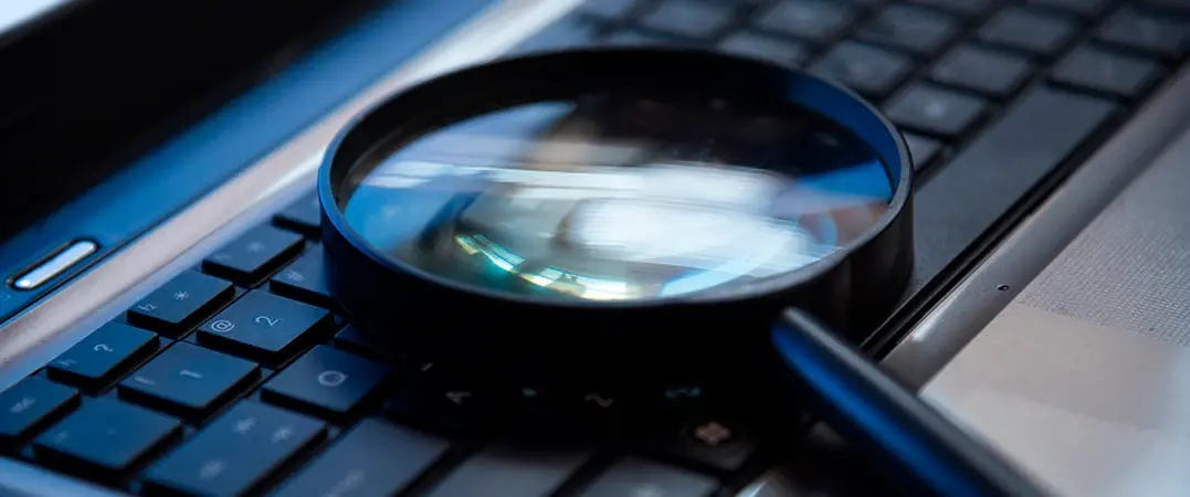 Lupa apoyada sobre el teclado de una computadora portátil